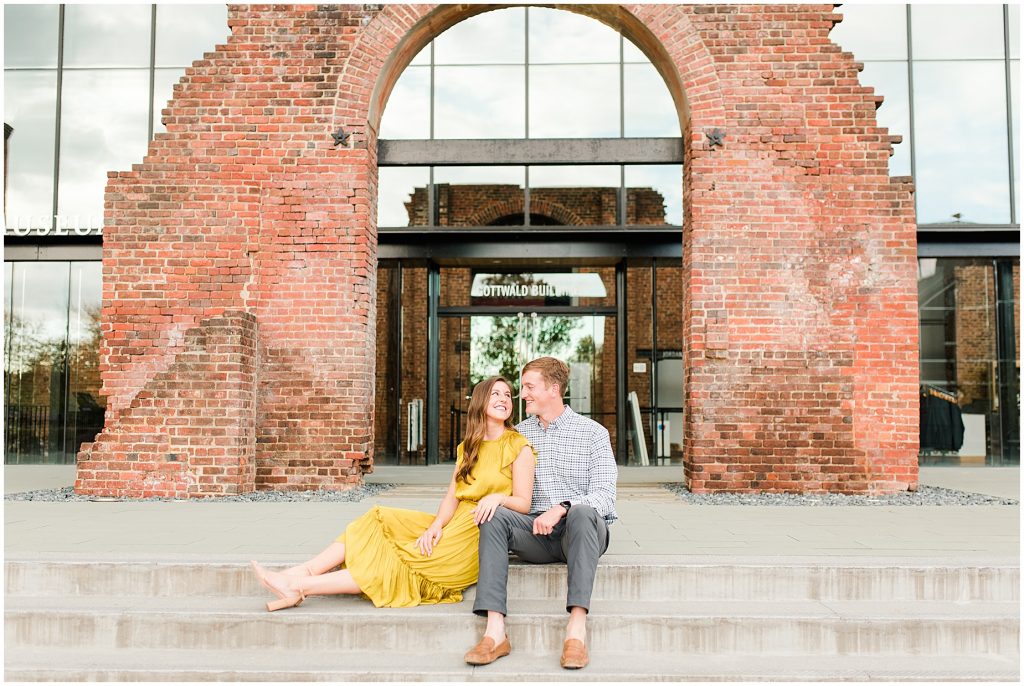 engagement couple sitting at brick arch at historic tredegar museum in richmond virginia
